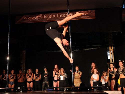 Foto von mir im Handspring an der Pole. Im Hintergrund stehen weitere Künstlerinnen und Künstler, die klatschen.